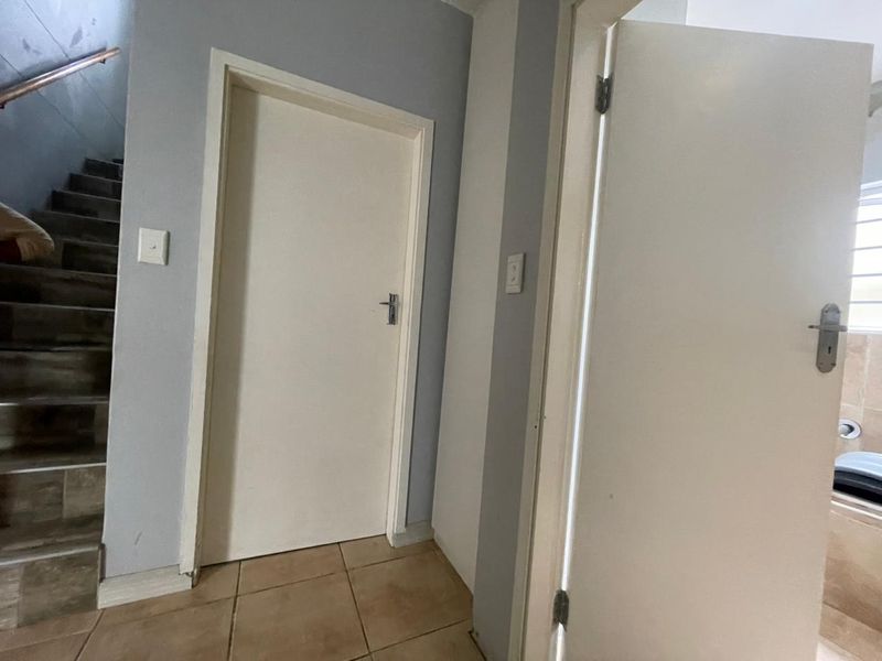 A functional hallway area featuring tiled flooring, internal doors, and access to a staircase.