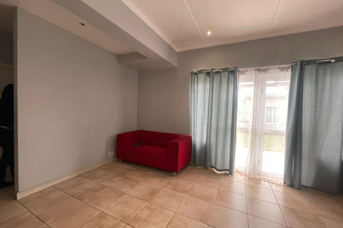 A living room featuring tiled flooring and a sliding glass door providing access to the exterior.