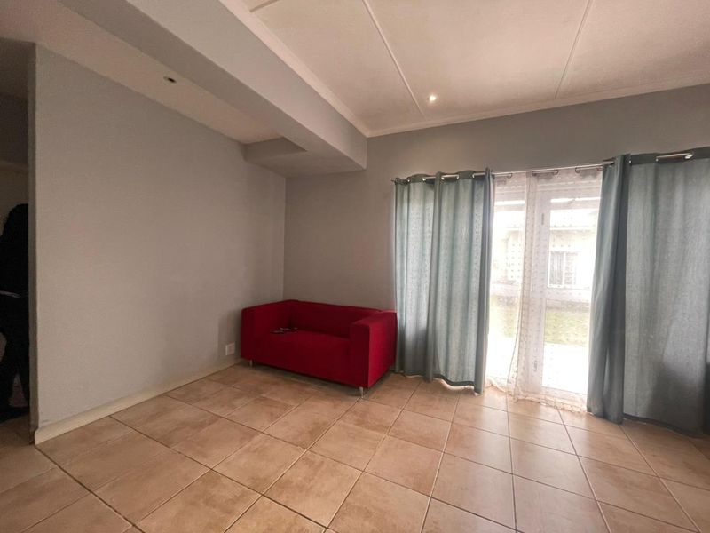 A living room featuring tiled flooring and a sliding glass door providing access to the exterior.