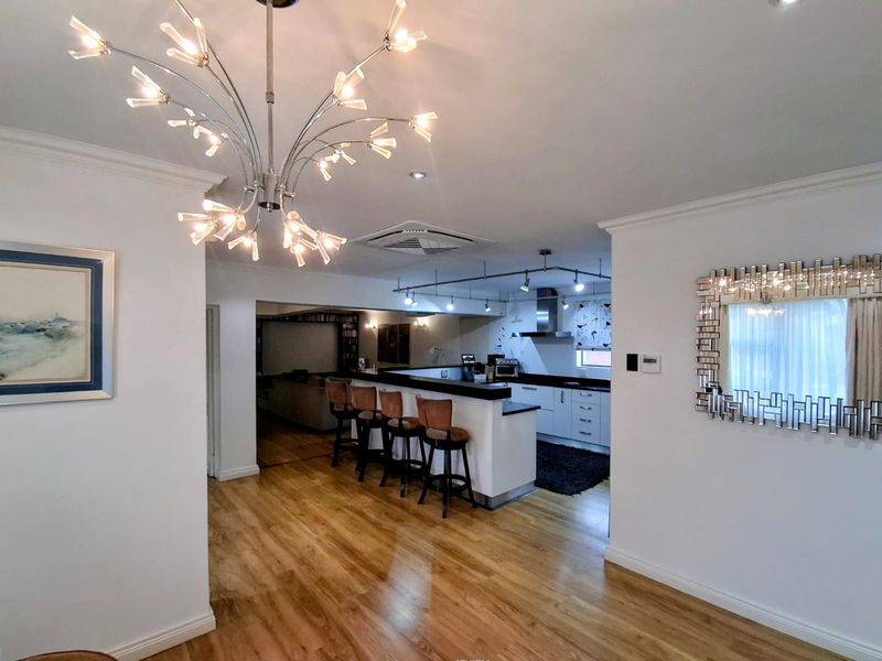 Open plan living and kitchen area featuring a breakfast bar, modern cabinetry, hardwood flooring, and recessed lighting, creating a spacious and functional home layout.