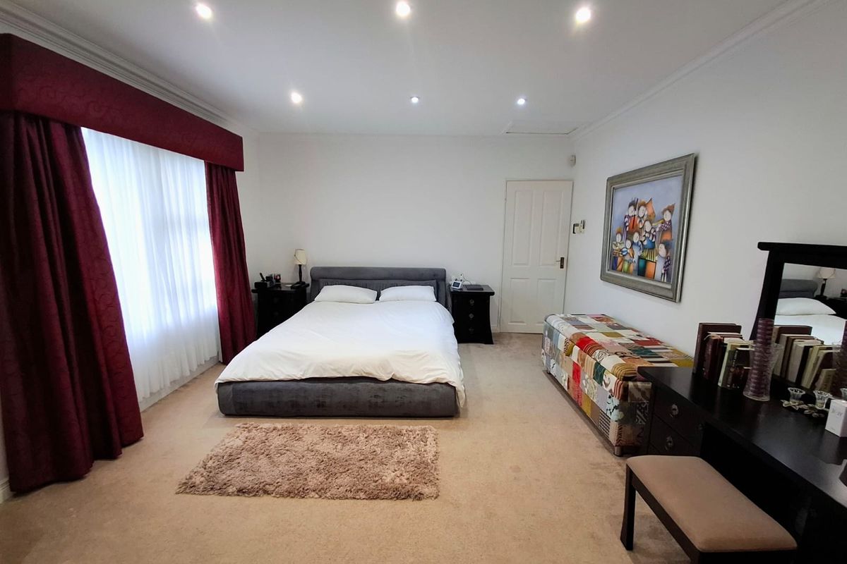 A spacious bedroom featuring neutral carpeting, recessed downlighting, and classic coving, providing a comfortable and well-maintained living space.