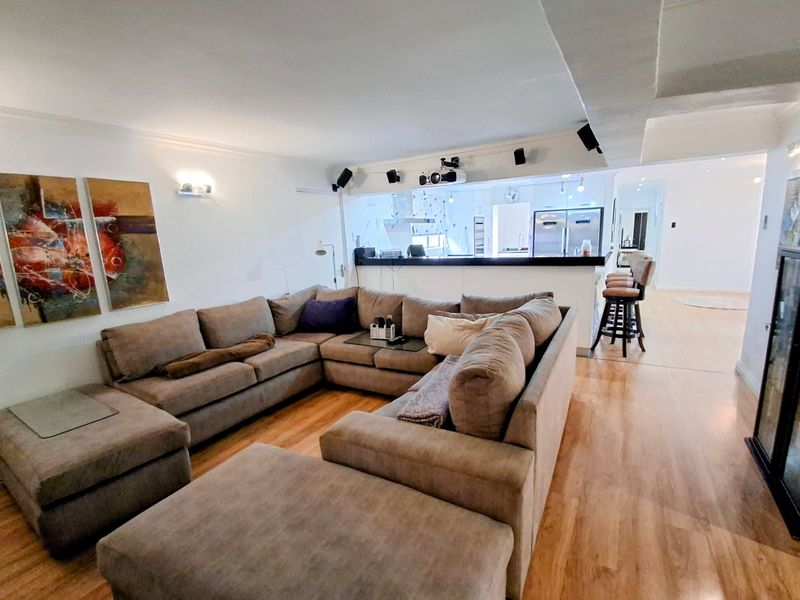 Spacious open-plan living area featuring hardwood flooring, a kitchen breakfast bar, and integrated projector setup, creating a versatile entertainment and dining space.