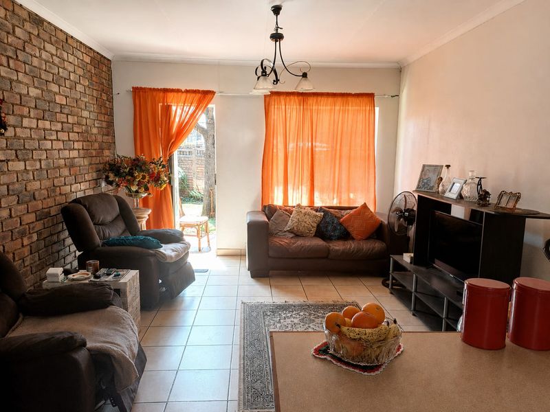 A living room featuring an exposed brick feature wall, tiled flooring, and a sliding glass door providing access to the outdoor area.