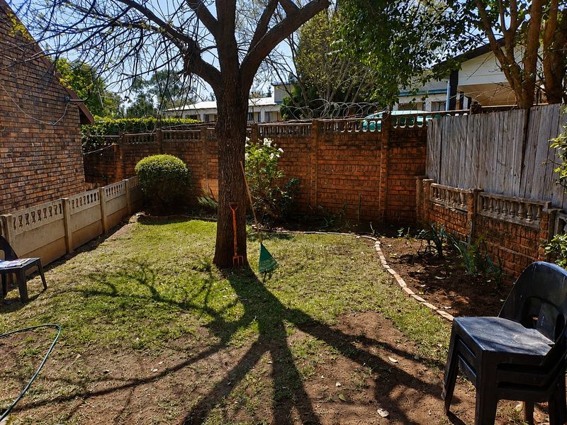 A private rear garden area featuring a mature tree, brick boundary walls, and precast concrete fencing, offering potential for landscaping and outdoor improvement.