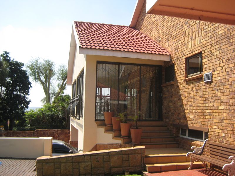 Rear exterior view of the duet property featuring a face brick facade, tiled staircase, and a secure sliding door entrance.