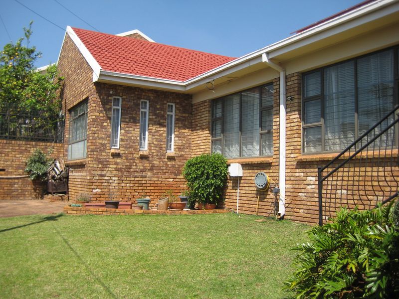 Rear view of a face brick duet property featuring a red tiled roof, aluminium window frames, and a small private garden area.