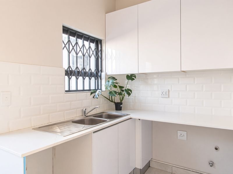 A clean and functional scullery featuring white cabinetry, a double stainless steel sink, and a classic subway tile backsplash.
