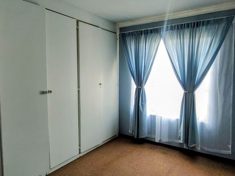 A clean, empty bedroom featuring built-in cupboards and carpeted flooring, offering a neutral space ready for personalization.