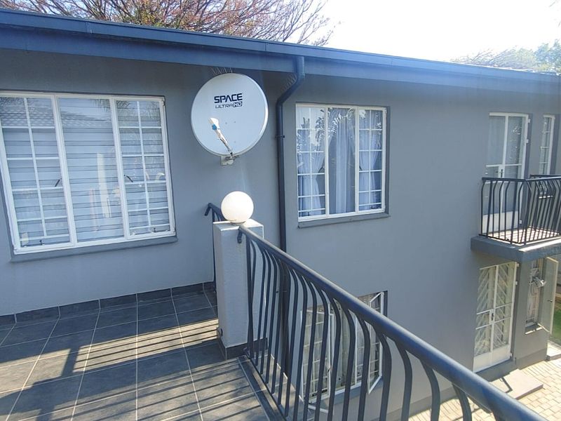 A spacious upper-level balcony featuring tiled flooring, secure metal balustrades, and direct access to the apartment interior through sliding doors.
