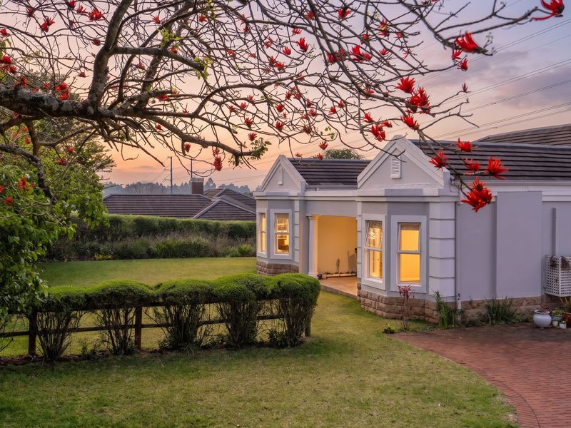 A well-maintained townhouse exterior featuring stone cladding, a tiled roof, and a covered patio overlooking a landscaped garden at sunset.