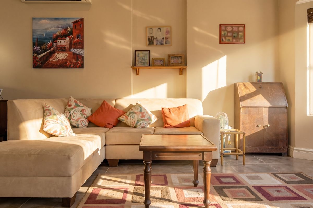 A sunlit living room featuring tiled flooring and a wall-mounted air conditioning unit, offering a warm and inviting atmosphere.