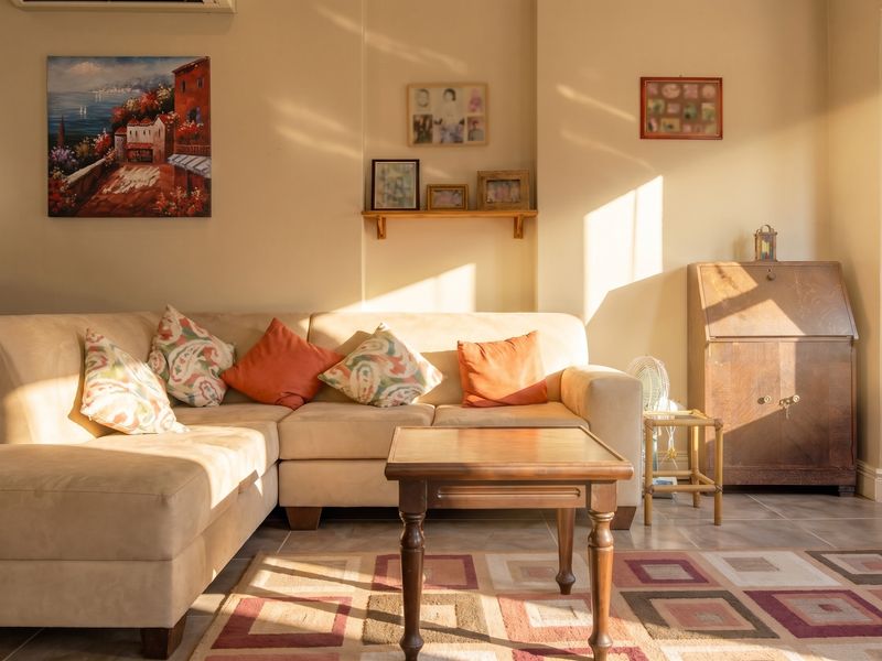 A sunlit living room featuring tiled flooring and a wall-mounted air conditioning unit, offering a warm and inviting atmosphere.
