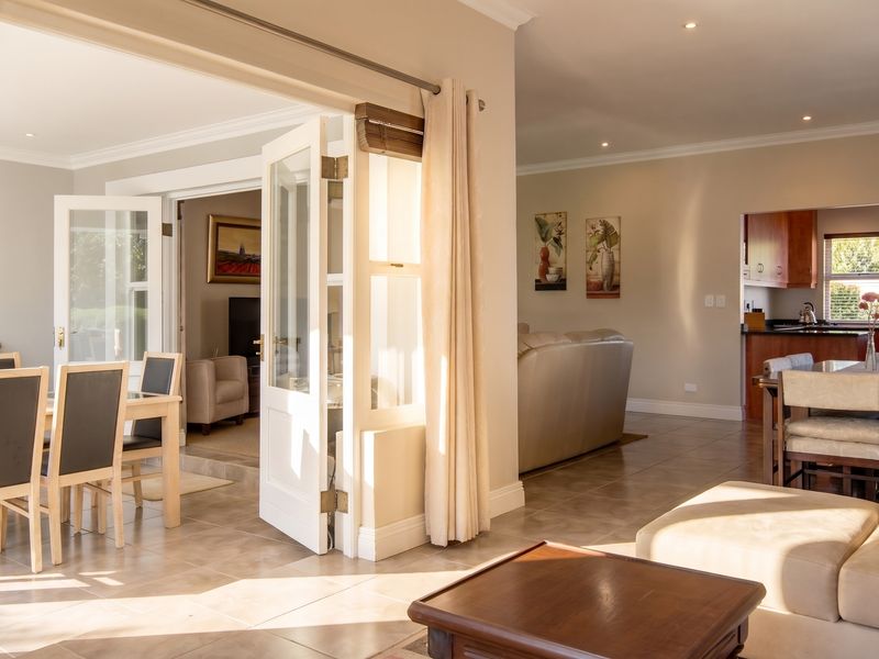 Spacious open-plan living and dining area featuring tiled flooring, recessed lighting, and seamless flow through french doors to an adjacent room.