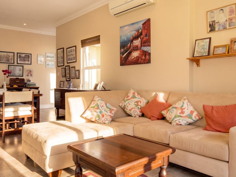 An open-plan living and dining area featuring tiled flooring, neutral wall tones, and a wall-mounted air conditioning unit.