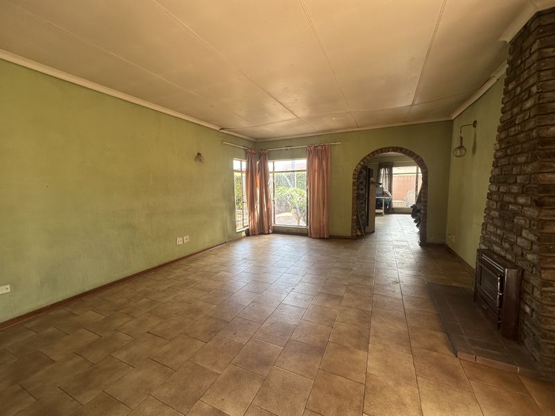 Spacious living room featuring tiled flooring, a prominent brick fireplace with a built-in stove, and an arched entryway leading to an adjacent space.