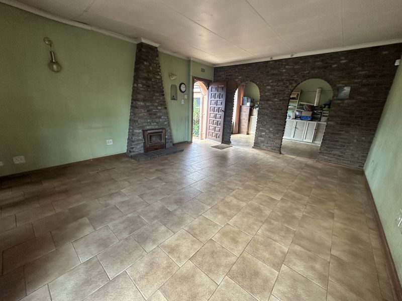 Spacious living area featuring a stone fireplace, tiled flooring, and distinctive brick archways leading to an adjacent space.