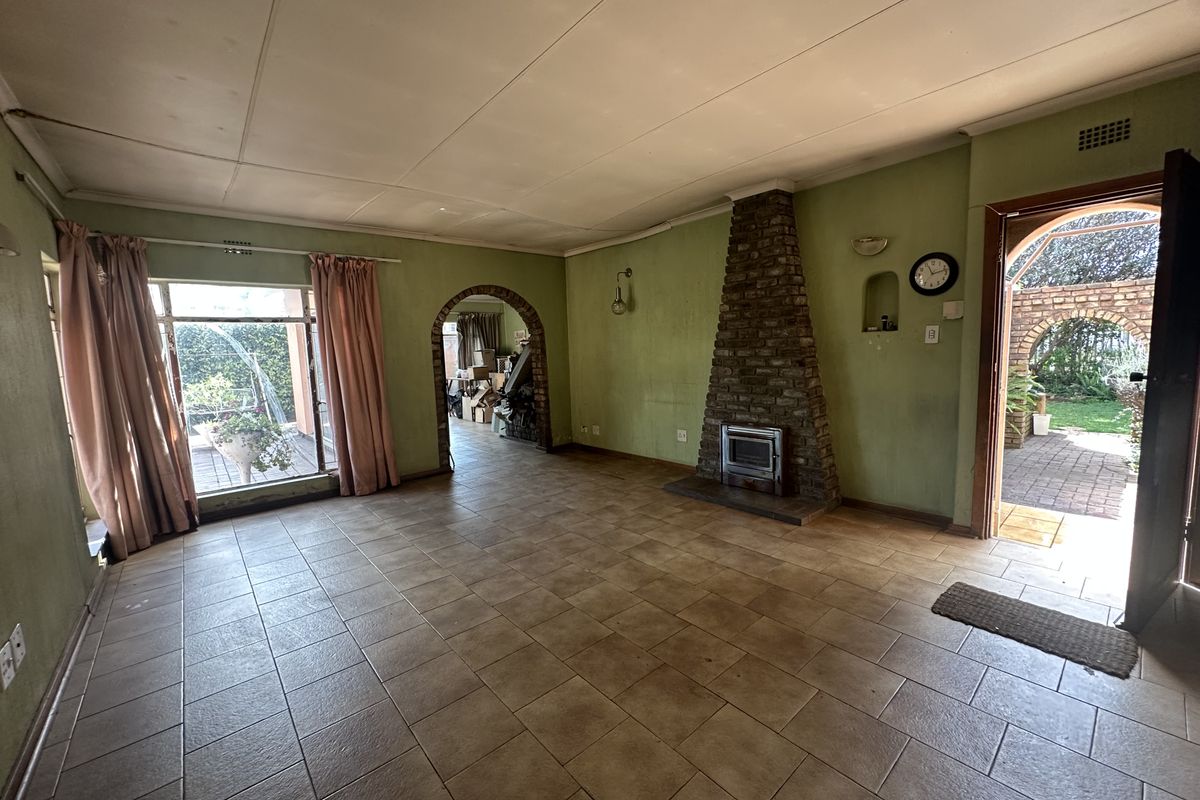 Spacious living room featuring a brick fireplace with a wood-burning stove, tiled flooring, and an arched entryway leading to adjacent living spaces.
