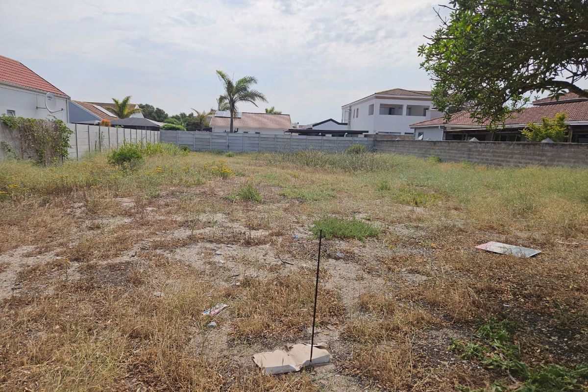 A vacant residential plot featuring a level surface enclosed by precast concrete boundary walls, ready for development.