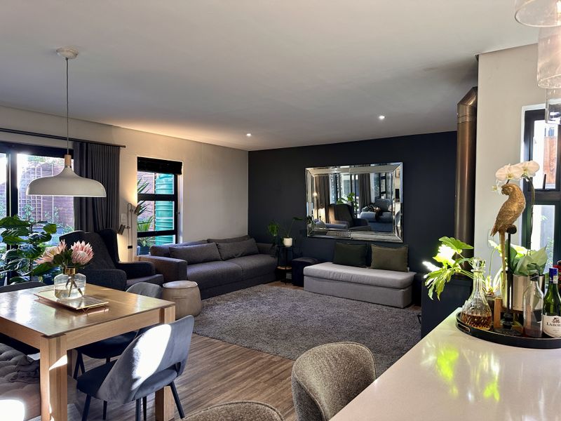 Spacious open-plan living and dining area featuring a modern freestanding fireplace, laminate flooring, and large sliding doors providing access to the outdoor space.
