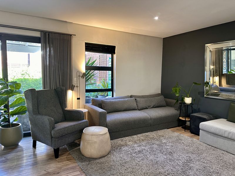 A well-maintained living room featuring laminate flooring, recessed lighting, and a large sliding glass door providing access to the outdoor area.
