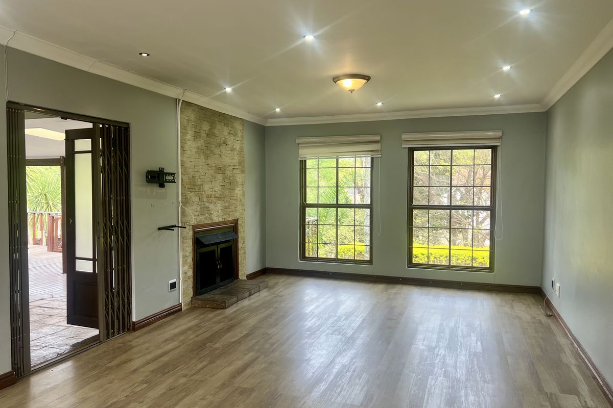 Spacious living room featuring a stone-clad fireplace, laminate flooring, recessed lighting, and direct access to an outdoor patio area.