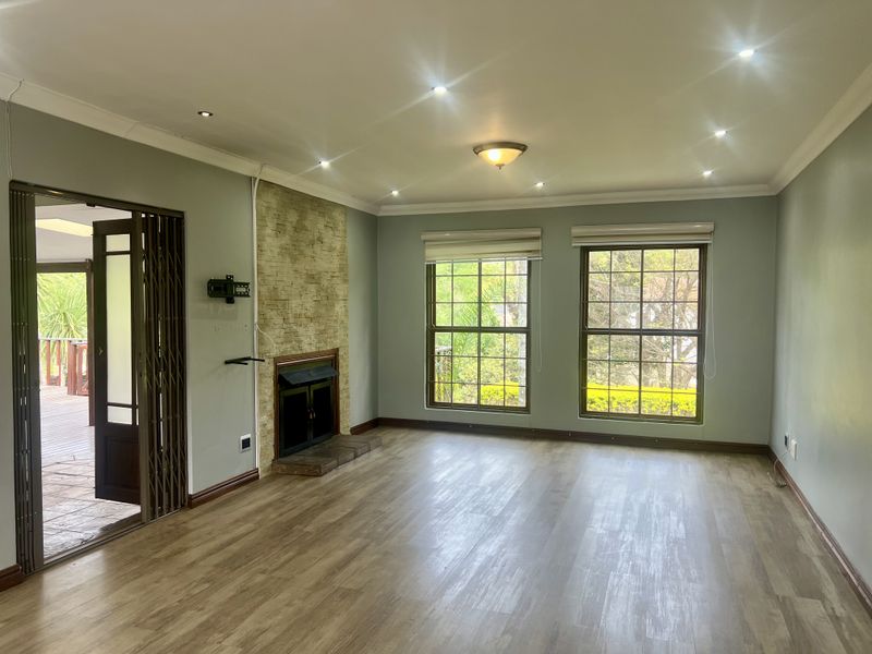 Spacious living room featuring a stone-clad fireplace, laminate flooring, recessed lighting, and direct access to an outdoor patio area.
