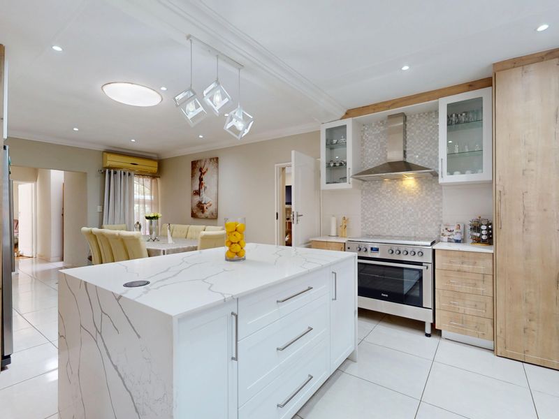 Modern open-plan kitchen featuring a central island with quartz countertops, high-end cabinetry, and integrated appliances, seamlessly flowing into the dining area.