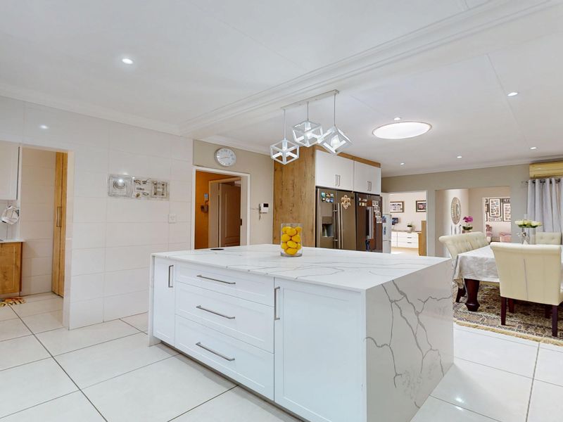 Spacious open-plan kitchen featuring a large central island with quartz countertops, modern cabinetry, and integrated appliances, seamlessly flowing into the dining area.
