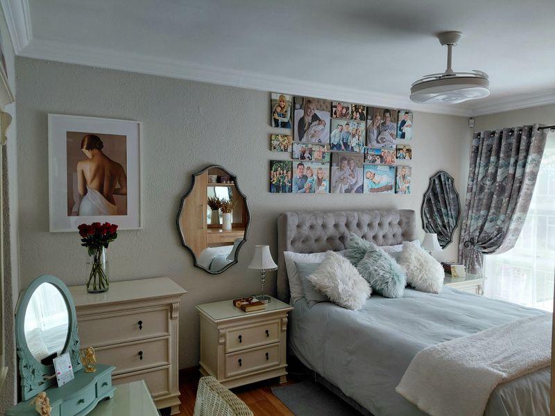 A well-maintained bedroom featuring crown molding, a ceiling fan, and hardwood flooring, offering a comfortable and inviting living space.