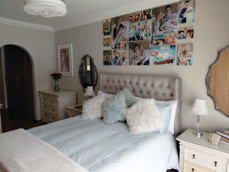 A well-maintained bedroom featuring an arched doorway, decorative coving, and a central ceiling light fixture.