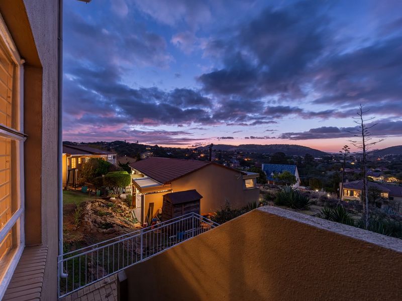 A scenic elevated view overlooking a residential neighborhood at dusk, featuring a metal railing and surrounding suburban landscape.