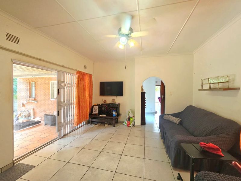 Living room featuring tiled flooring, a ceiling fan, and a sliding glass door providing access to the outdoor patio area.