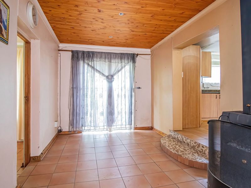 Living area featuring a wood-paneled ceiling, tiled flooring, and a built-in fireplace on a raised platform, with direct access to the outdoors.