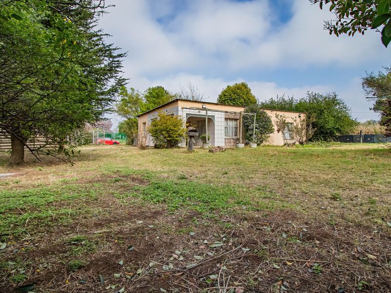 A view of the rear elevation of the small holding dwelling, featuring a tiled patio area and surrounding garden space.