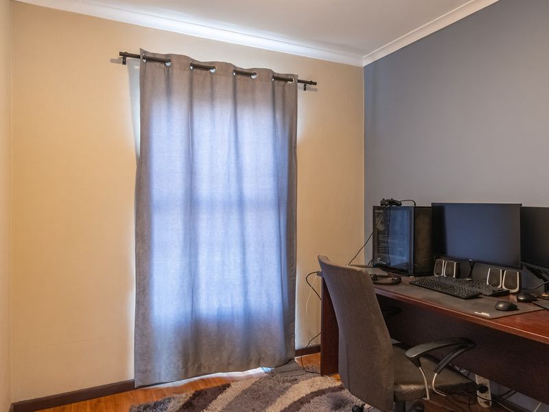 A bedroom featuring hardwood flooring, a curtain rod, and coving, currently utilized as a home office space.