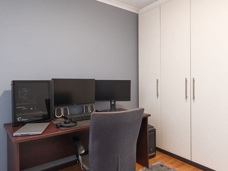 A bedroom featuring laminate flooring and a large white built-in wardrobe with modern handles.