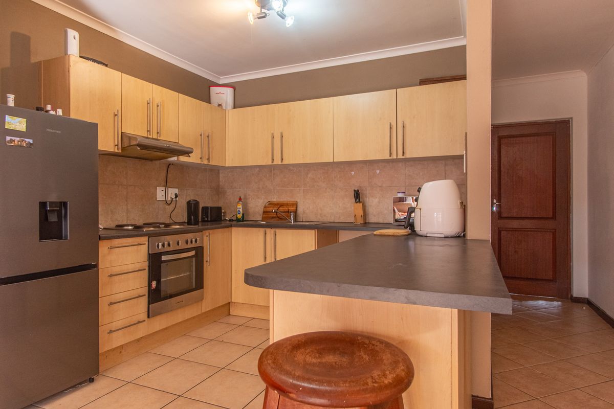 A functional kitchen featuring light wood cabinetry, dark laminate countertops, a breakfast bar, and tiled flooring, providing a practical layout for daily use.