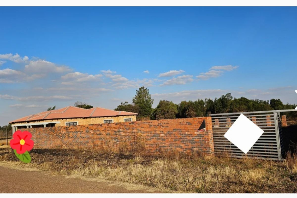 Front view of a residential property featuring a face brick boundary wall, metal sliding gate, and a tiled roof structure.