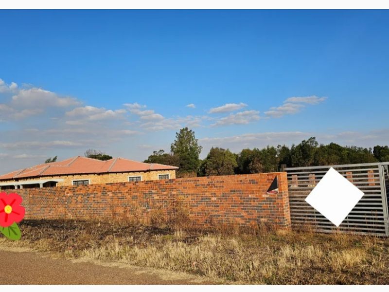 Front view of a residential property featuring a face brick boundary wall, metal sliding gate, and a tiled roof structure.