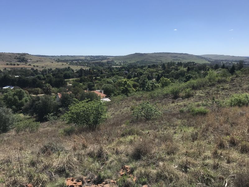 A wide-angle view overlooking the surrounding landscape, featuring rolling hills, natural vegetation, and distant residential properties.