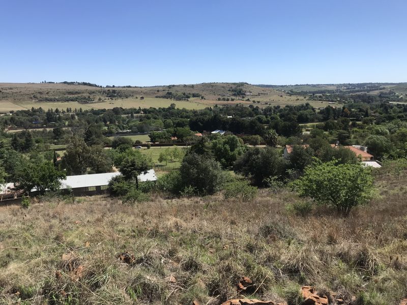 An elevated view overlooking the surrounding landscape, featuring rolling hills, mature trees, and distant residential properties.