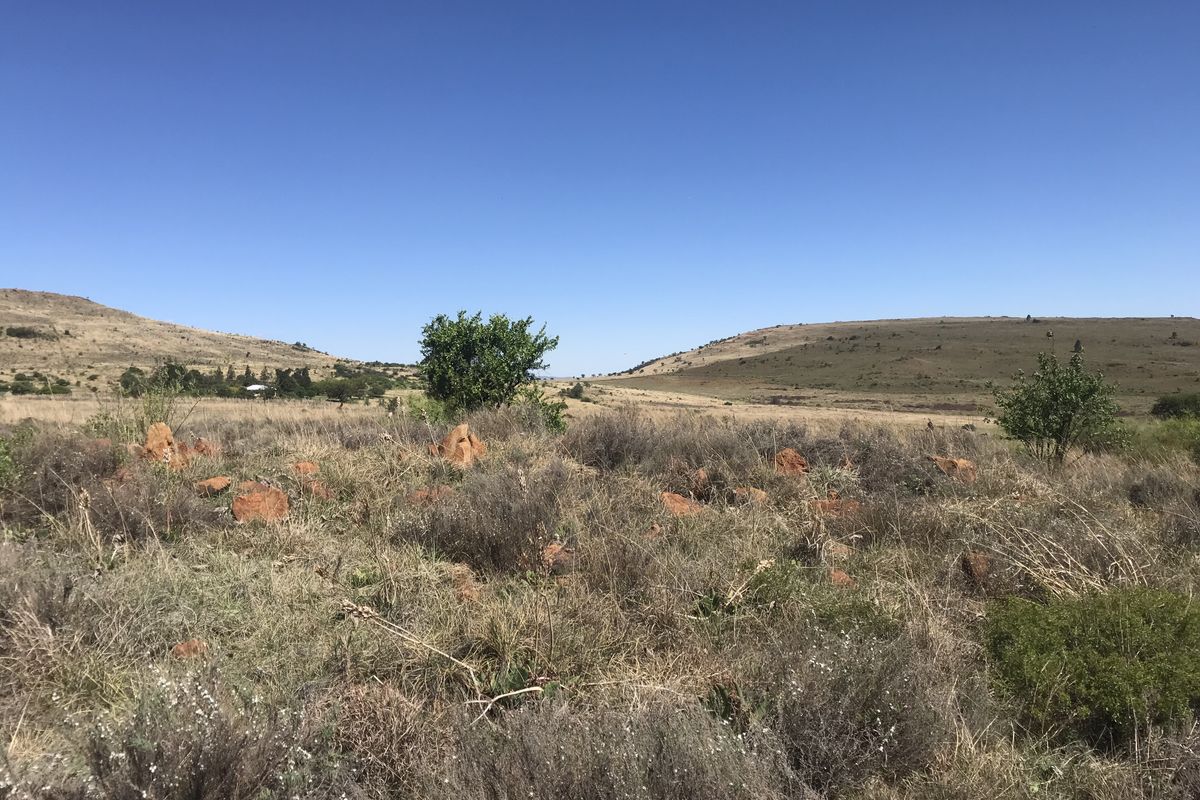 A wide-angle view of the vacant residential land featuring natural rocky terrain and open landscape under a clear blue sky.
