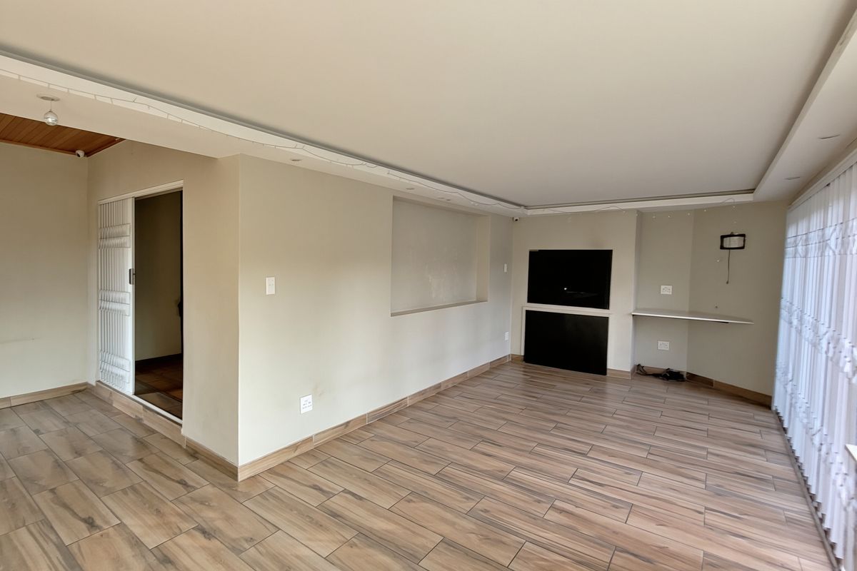 Spacious living area featuring wood-look tile flooring, a built-in fireplace, and a recessed wall niche, offering a clean and neutral foundation for living space.