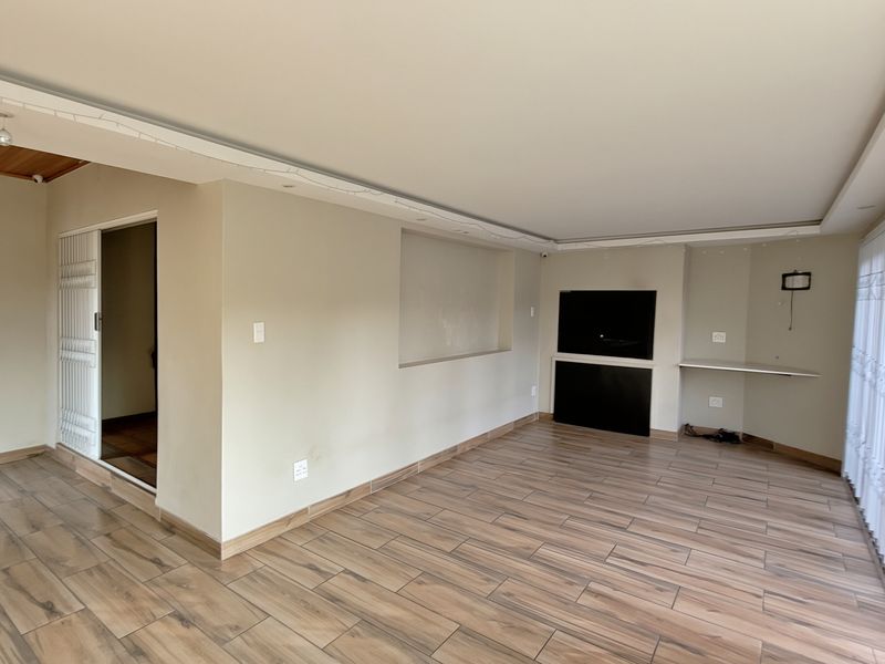 Spacious living area featuring wood-look tile flooring, a built-in fireplace, and a recessed wall niche, offering a clean and neutral foundation for living space.