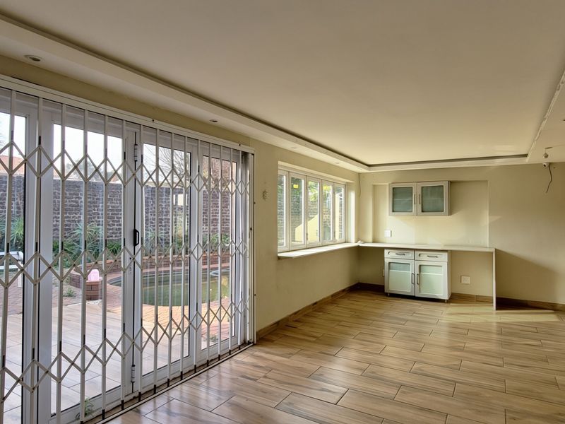 Spacious open-plan living area featuring tiled floors, recessed lighting, built-in cabinetry, and sliding doors leading to an outdoor patio and pool area.