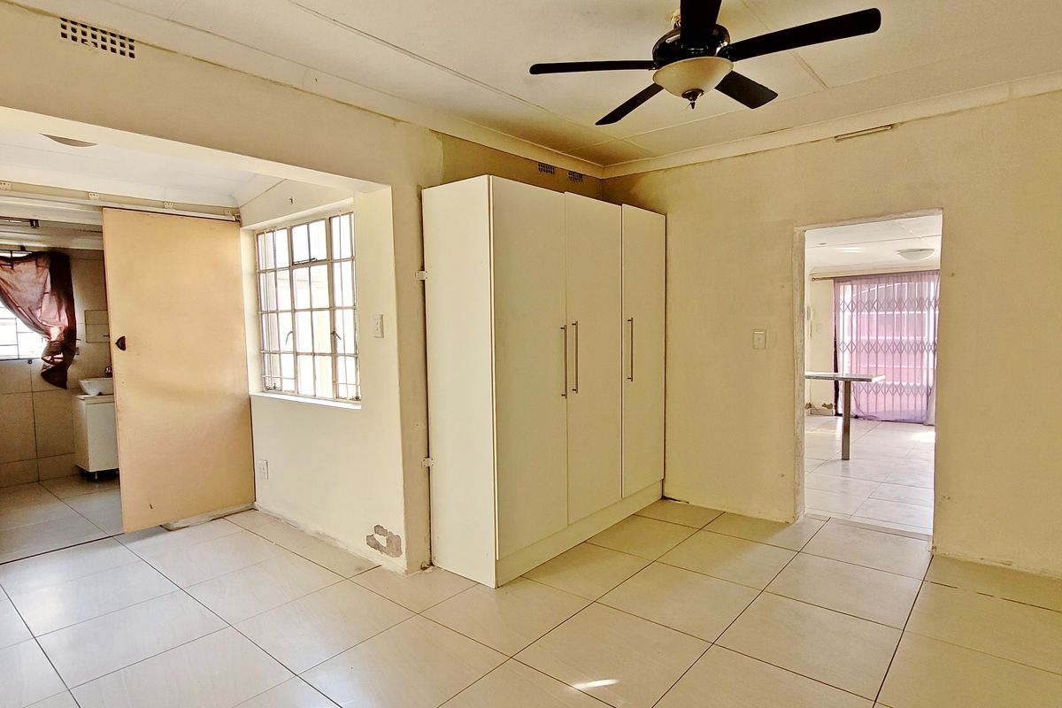 A bedroom featuring tiled flooring, a built-in wardrobe, and a ceiling fan, with access to adjacent living areas.