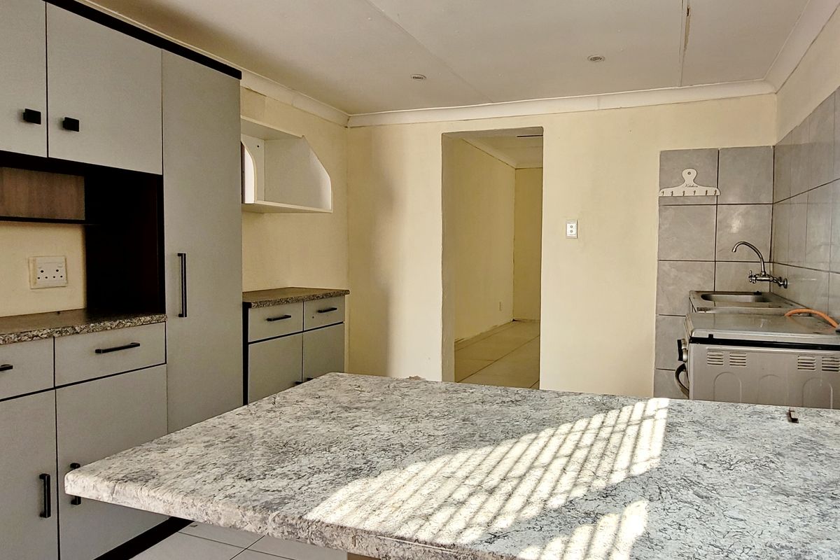 A functional kitchen featuring built-in cabinetry, laminate countertops, and a tiled backsplash, offering a clean and practical space ready for personalization.