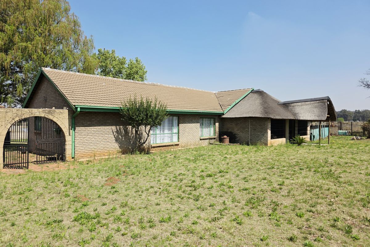 Rear view of a facebrick small holding dwelling featuring a combination of tiled and thatched roofing with an attached covered patio area.