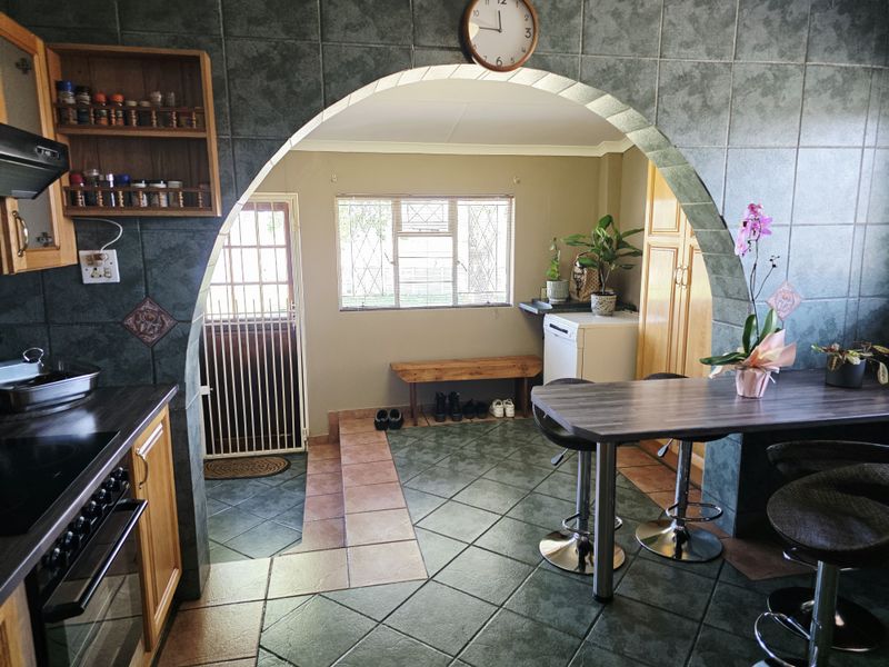 Kitchen area featuring dark tiled finishes, an arched transition to an adjacent utility space, and built-in cabinetry with integrated cooking appliances.