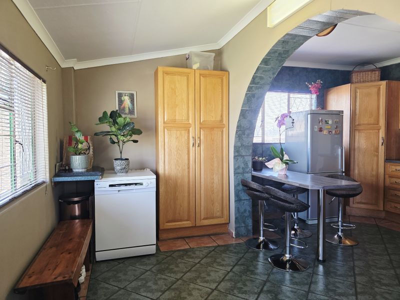 A functional kitchen area featuring wooden cabinetry, a breakfast bar with an arched transition, and tiled flooring.